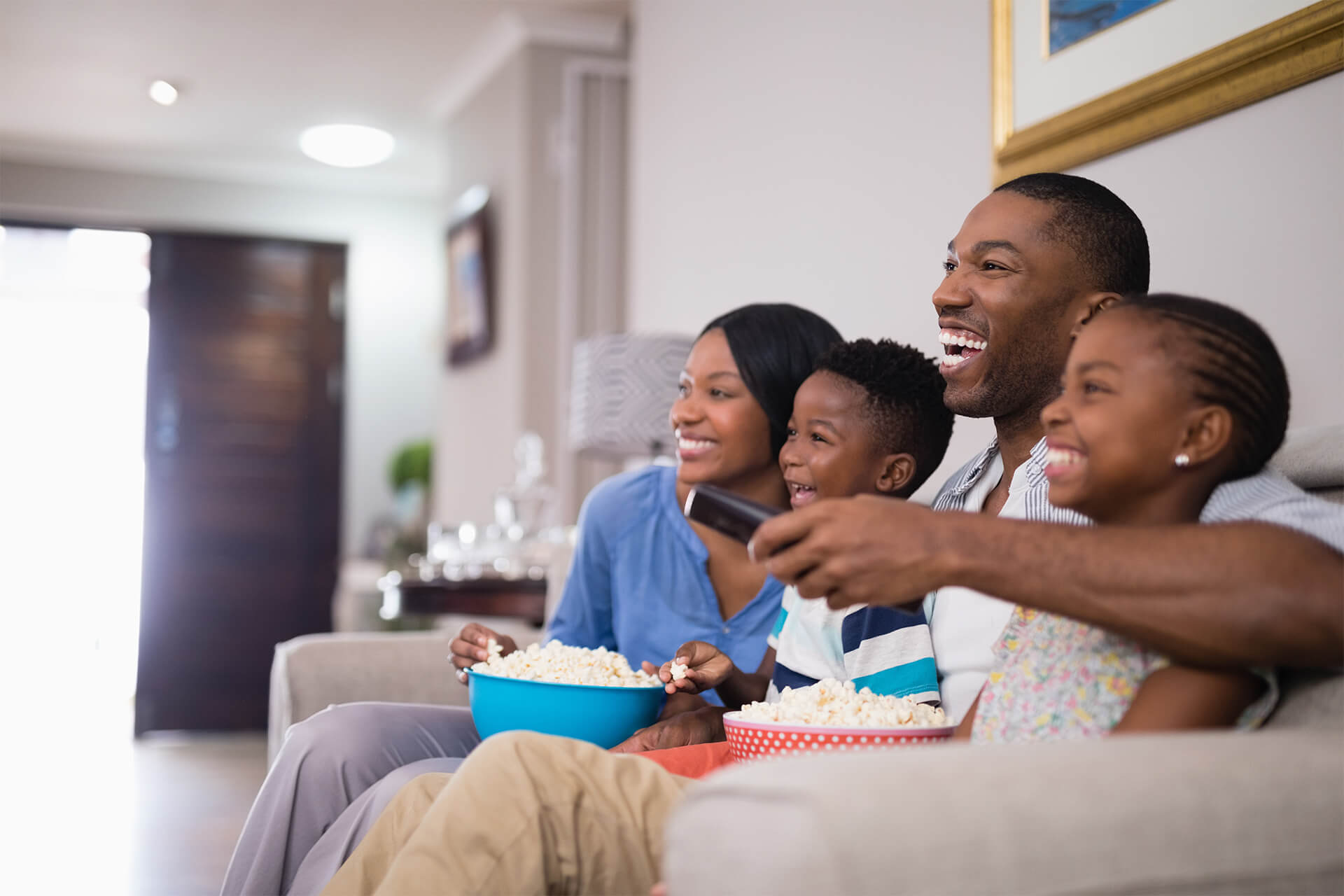 family sitting on couch happily watching television