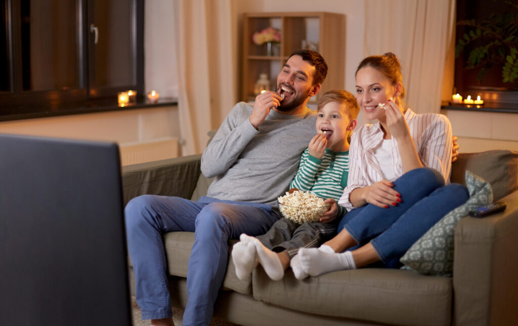 happy family with popcorn watching tv at home